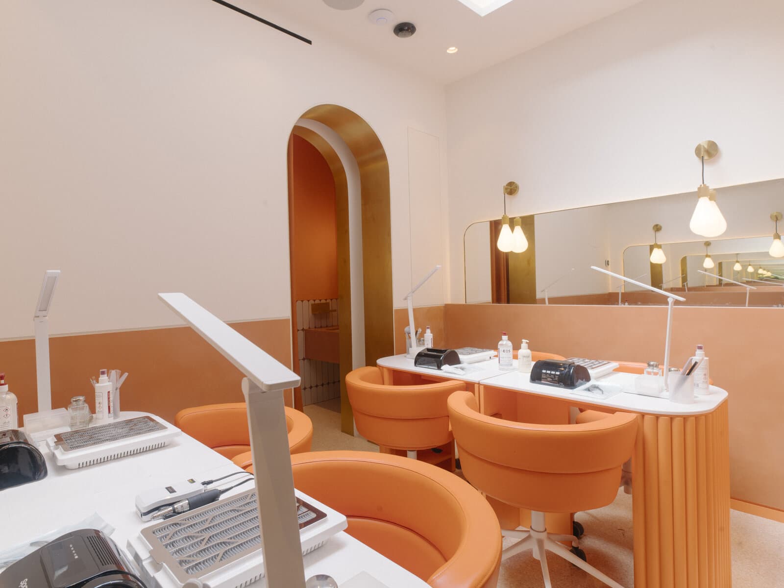 The CONA nail studio interior with terracotta walls, soft lighting and curved chairs