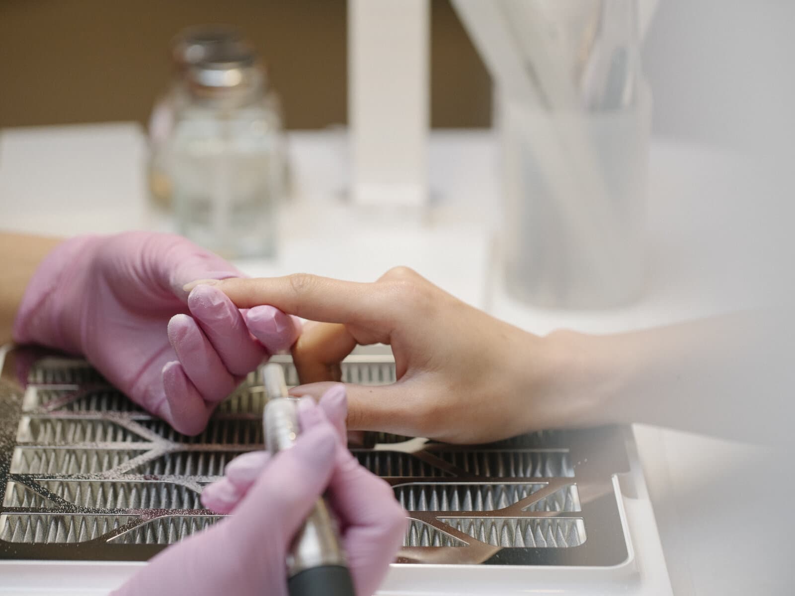 Close-up of a nail technician finishing detailed work on a client's hand